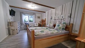 A bedroom with a wooden bed, a desk, a chair, and a television.