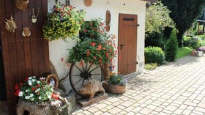 A rustic building with a wooden door, a wheelbarrow, and various animal head decorations.