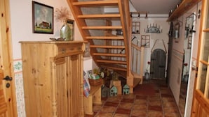 A kitchen with a wooden staircase, a cabinet, and a tiled floor.
