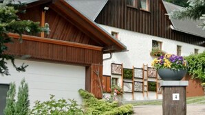 A traditional wooden house with a white exterior, a wooden porch, and a flower pot with colorful flowers.