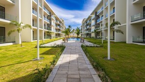 Un hôtel moderne doté d’une piscine centrale, entouré de pelouses bien entretenues et de palmiers.