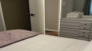 Un dormitorio con cama, cómoda y una puerta.