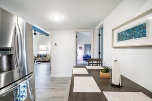 A modern kitchen with a stainless steel refrigerator, a dining area with a table and chairs, and a living room with a sofa and a coffee table. - Big 6BR Beach Getaway for 20 | Near Ferry, 3 Units (Bolivar Peninsula)