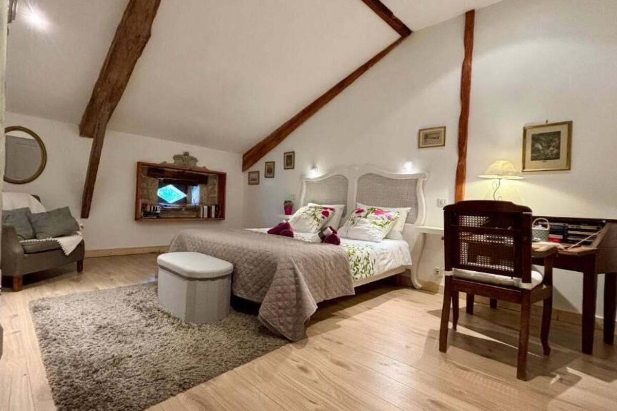 A bedroom with a bed, a chair, a desk, and a small table.