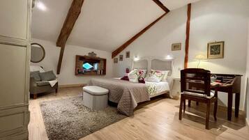 Une chambre à coucher avec un lit, une chaise, un bureau et une petite table.