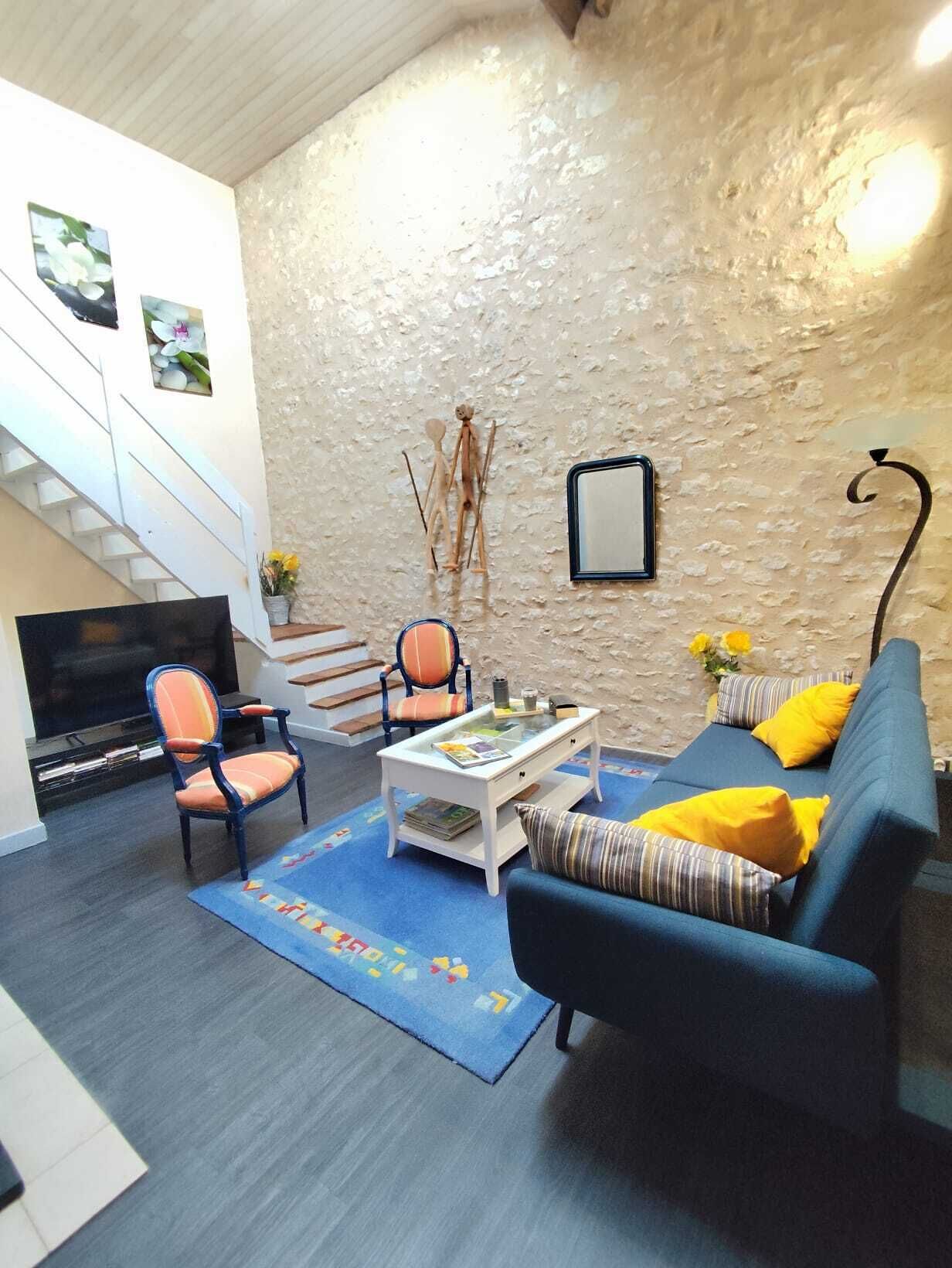 A living room with a staircase, a sofa, a chair, a coffee table, and a TV.