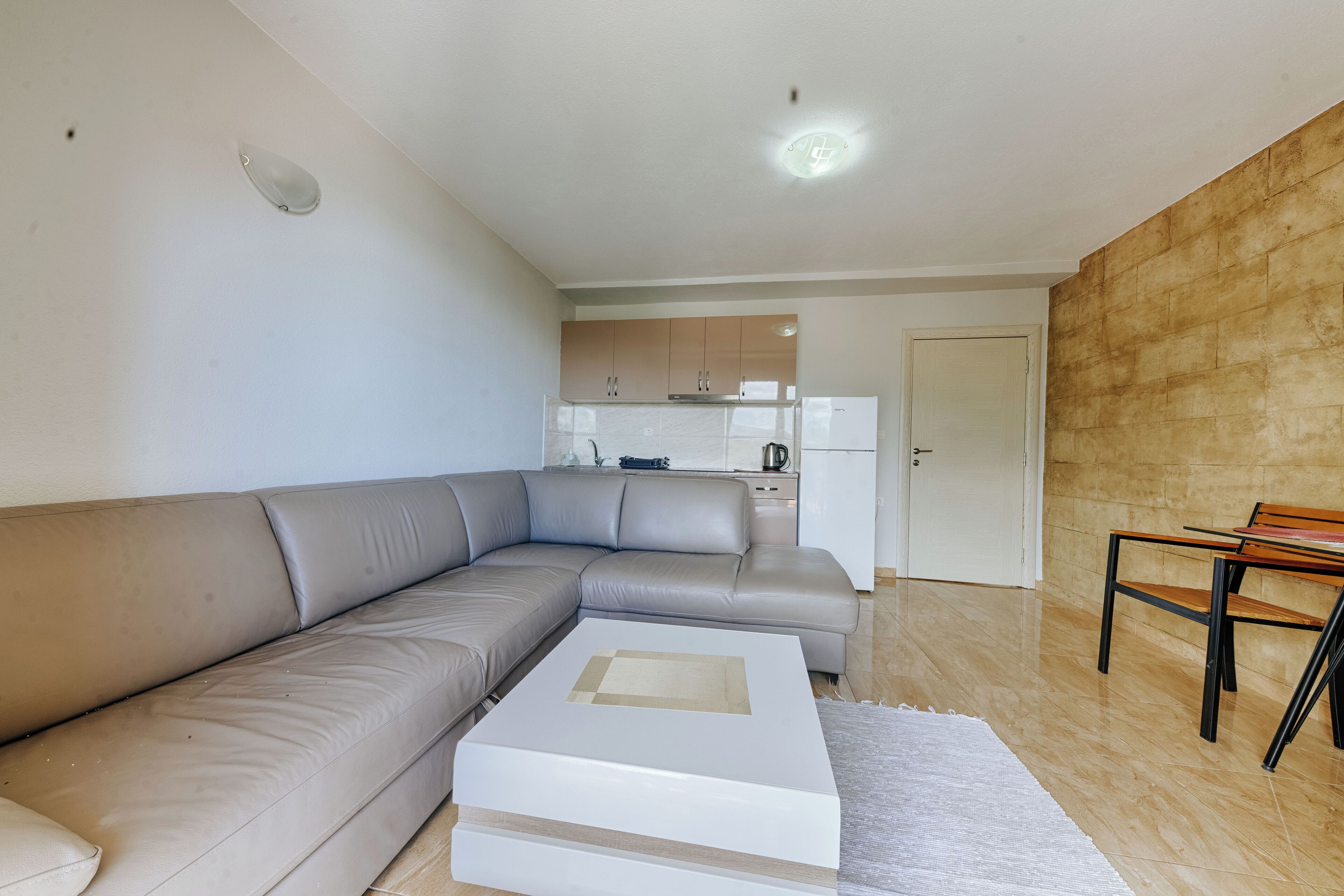 Un salon moderne avec un canapé d’angle, une table basse et un coin repas comprenant une chaise.