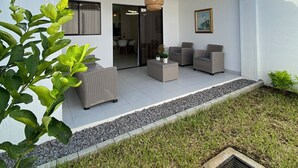Une maison moderne dotée d’un patio, de mobilier d’extérieur et d’une pelouse bien entretenue.