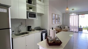 Una cocina moderna con armarios blancos, una isla central y una zona de comedor con sofá y mesa.