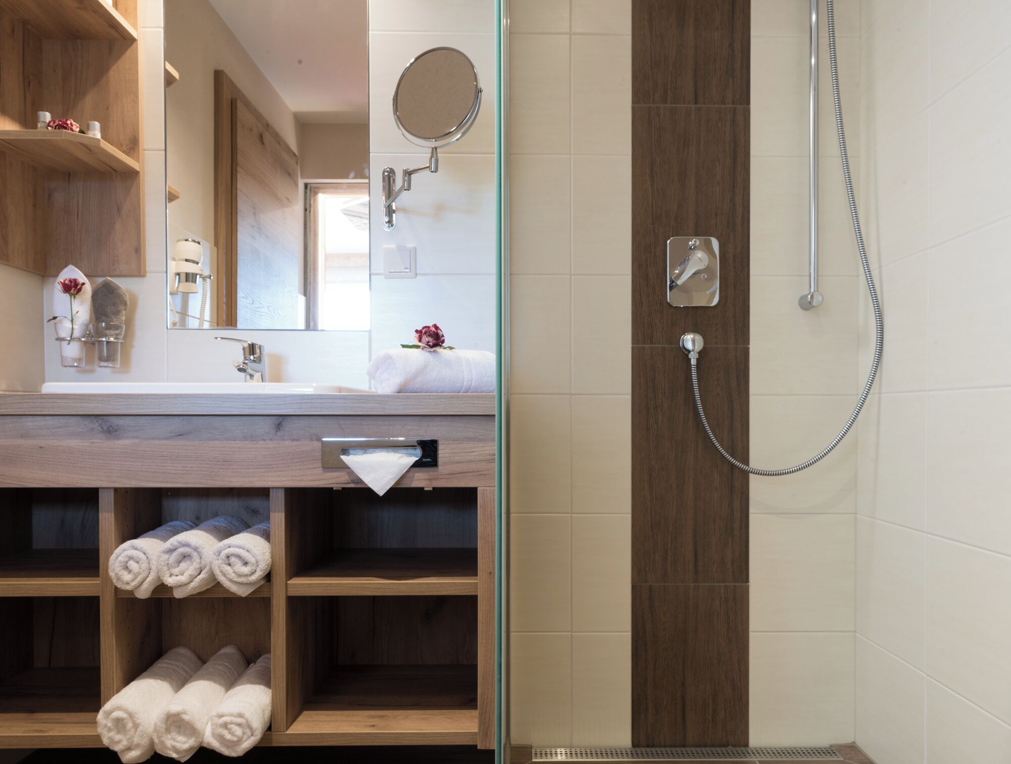 Un baño moderno con tocador de madera, espejo, toallero y zona de ducha.