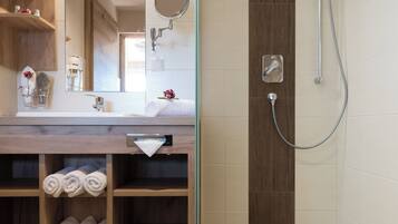 Un baño moderno con tocador de madera, espejo, toallero y zona de ducha.