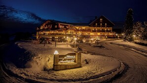 Un hotel grande de varios pisos con un camino cubierto de nieve y letreros iluminados.
