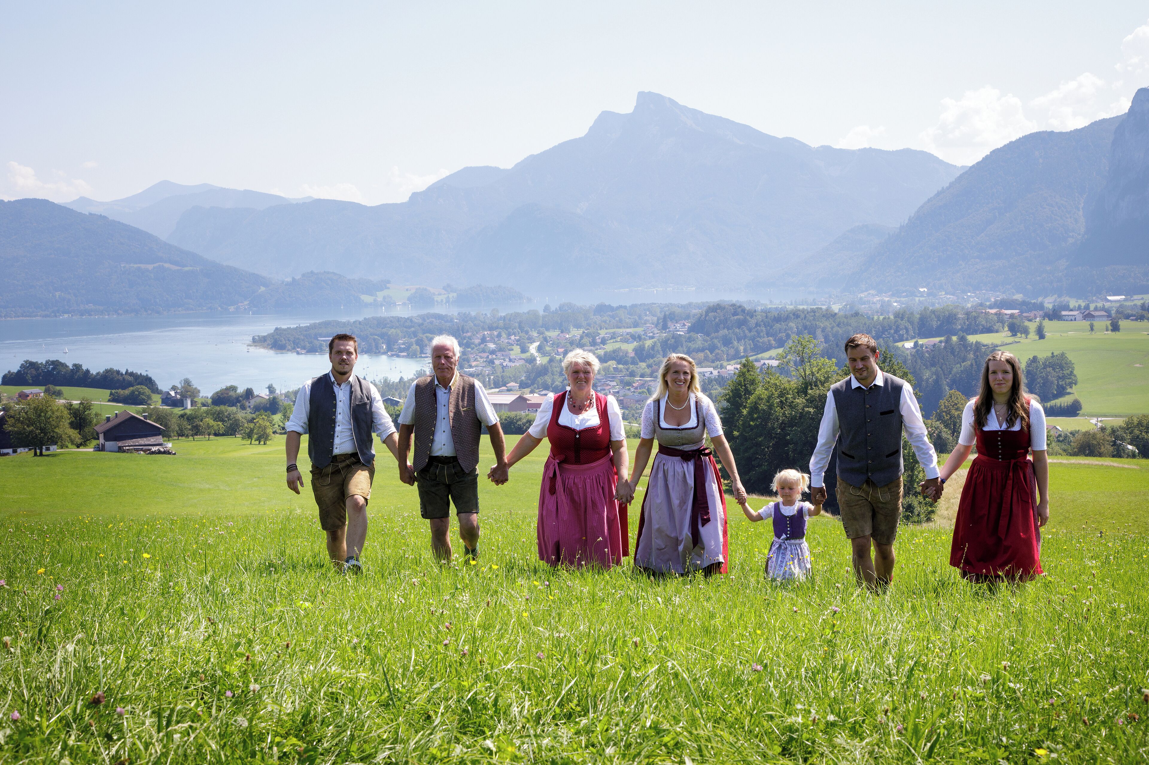 A family walking on a grassy field with a mountainous landscape in the background.