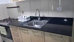 Eine moderne Küche mit Spüle aus Edelstahl, einem Gasherd und beigen Schränken.