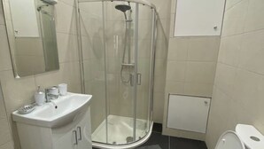 Un baño con ducha de vidrio, lavamanos con espejo y retrete.
