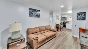 A modern living room with a brown sofa, a side table with a lamp, and artwork on the walls. - Main Lineup Apt 4 - All Star Baseball Rentals (Oneonta)