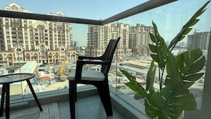 A balcony with a view of a cityscape, a potted plant, and a table with chairs. - Modern Studio with Balcony in Dubai Sports City (Dubai)
