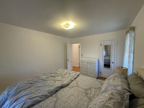 Ein Schlafzimmer mit Bett, Kommode und einer Tür zu einem anderen Raum.