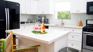 A modern kitchen with white cabinets, a black refrigerator, a microwave, a stove, and a sink. - Charming 3bdrm villa w/ panoramic ocean views, pool & patio, 5 min walk to beach (Providenciales)