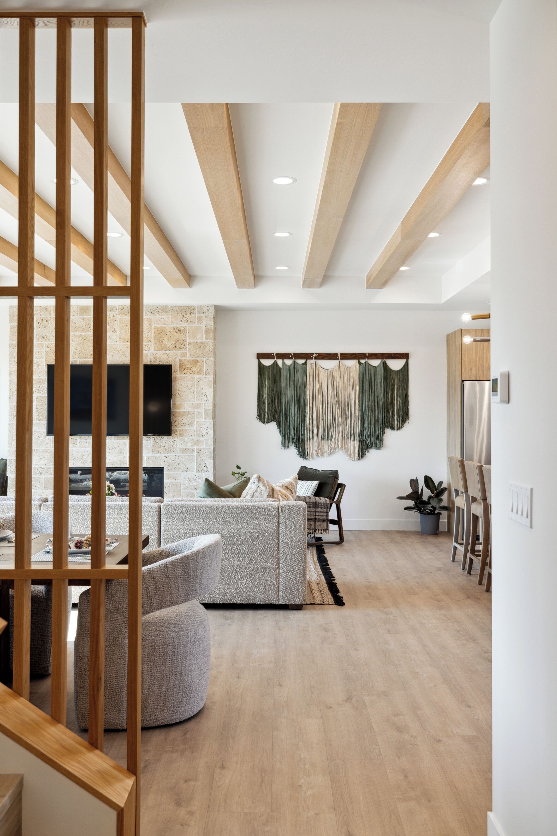A modern living room with a stone accent wall, a flat-screen TV, and a wooden ceiling.