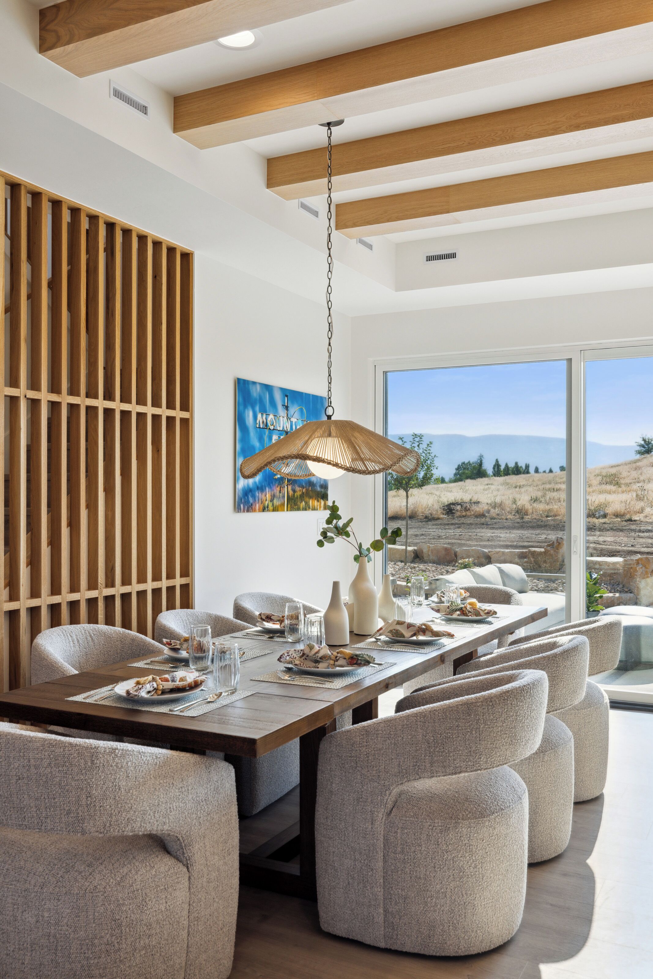 Un espace repas moderne avec un plafond en bois, une grande fenêtre donnant sur l’extérieur et une table à manger dressée avec des assiettes et des verres.