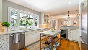 A modern kitchen with white cabinetry, a stainless steel dishwasher, and a central island with a bowl of fruit. - 4BR Pool Home | Pet-Friendly | Glen Ellen | Near Jack London Park | Sleeps 8 (Glen Ellen)