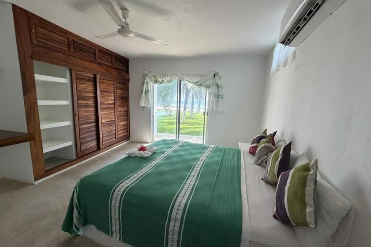 A bedroom with a bed, a wardrobe, a ceiling fan, and a window with curtains.