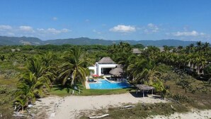 A resort with a pool, palm trees, and a view of mountains. - Casa Del Carmen (Santa María Colotepec)