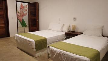 A hotel room with two single beds, a wooden wardrobe, a painting on the wall, and a bedside table with a lamp.