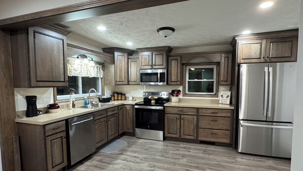 A modern kitchen with wooden cabinets, stainless steel appliances, and a large refrigerator.