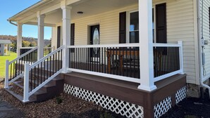 A two-story house with a covered porch, a front door with a decorative glass panel, and a small porch seating area.