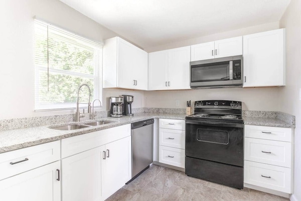 Full kitchen with range, microwave, dishwasher and coffee makers. Ample cabinets and worktop areas, with double sink.