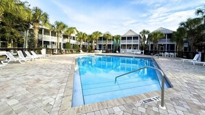 A swimming pool with lounge chairs and palm trees. - Beautiful Beach Cottage - dog friendly by pool and hottub (Port St. Joe)