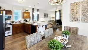 A spacious kitchen with wooden cabinets, a dining area with wicker chairs, and a chandelier. - Beautiful Beach Cottage - dog friendly by pool and hottub (Port St. Joe)