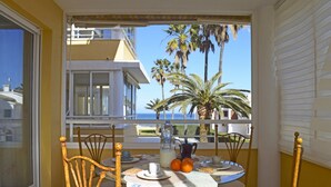 A balcony with a table set for breakfast, overlooking a coastal view with palm trees and a building in the background. - 07 Ap2206 in Denia With 2 Bedrooms and 2 Bathrooms (Denia)