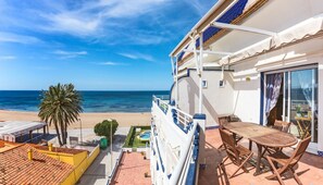 Varanda com vista para a praia, piscina e mesa com cadeiras.