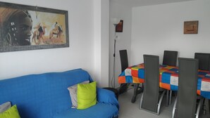 A room with a blue sofa, a dining table with chairs, and a painting on the wall. - Ap2133 in Denia With 2 Bedrooms and 1 Bathrooms (Denia)