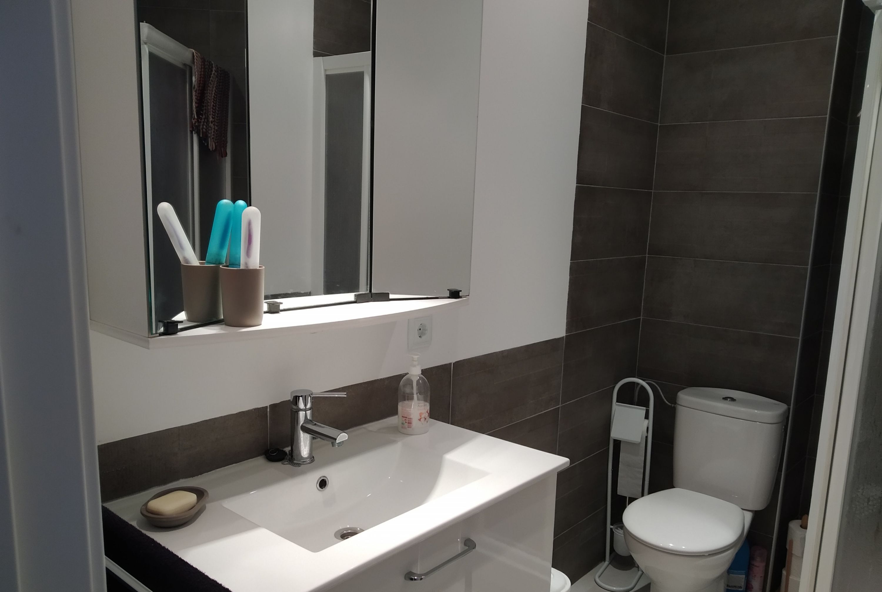 A modern bathroom with a white sink, mirror, and toilet.