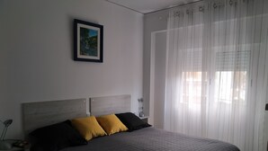 A bedroom with a bed, a nightstand, a lamp, a framed picture on the wall, and sheer curtains. - Ap2133 in Denia With 2 Bedrooms and 1 Bathrooms (Denia)