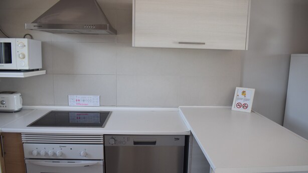 A compact kitchen with a microwave, toaster, stove, and dishwasher. - 09 At1101 in Denia With 1 Bedrooms and 2 Bathrooms (Denia)