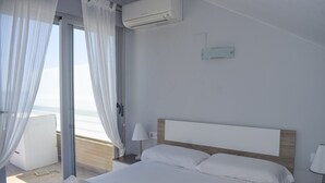 A hotel room with a bed, a nightstand, a lamp, an air conditioning unit, and a view of the beach through the window. - 09 At1101 in Denia With 1 Bedrooms and 2 Bathrooms (Denia)