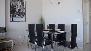 A dining area with a glass table, black chairs, a hanging light fixture, and a black and white photograph on the wall. - 09 At1101 in Denia With 1 Bedrooms and 2 Bathrooms (Denia)
