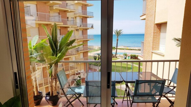 A balcony with a view of the sea, a potted plant, and two chairs. - Ap3212 in Denia With 3 Bedrooms and 2 Bathrooms (Denia)