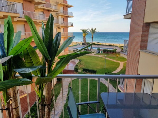 A balcony with a view of a beach, palm trees, and a well-maintained lawn. - Ap3212 in Denia With 3 Bedrooms and 2 Bathrooms (Denia)