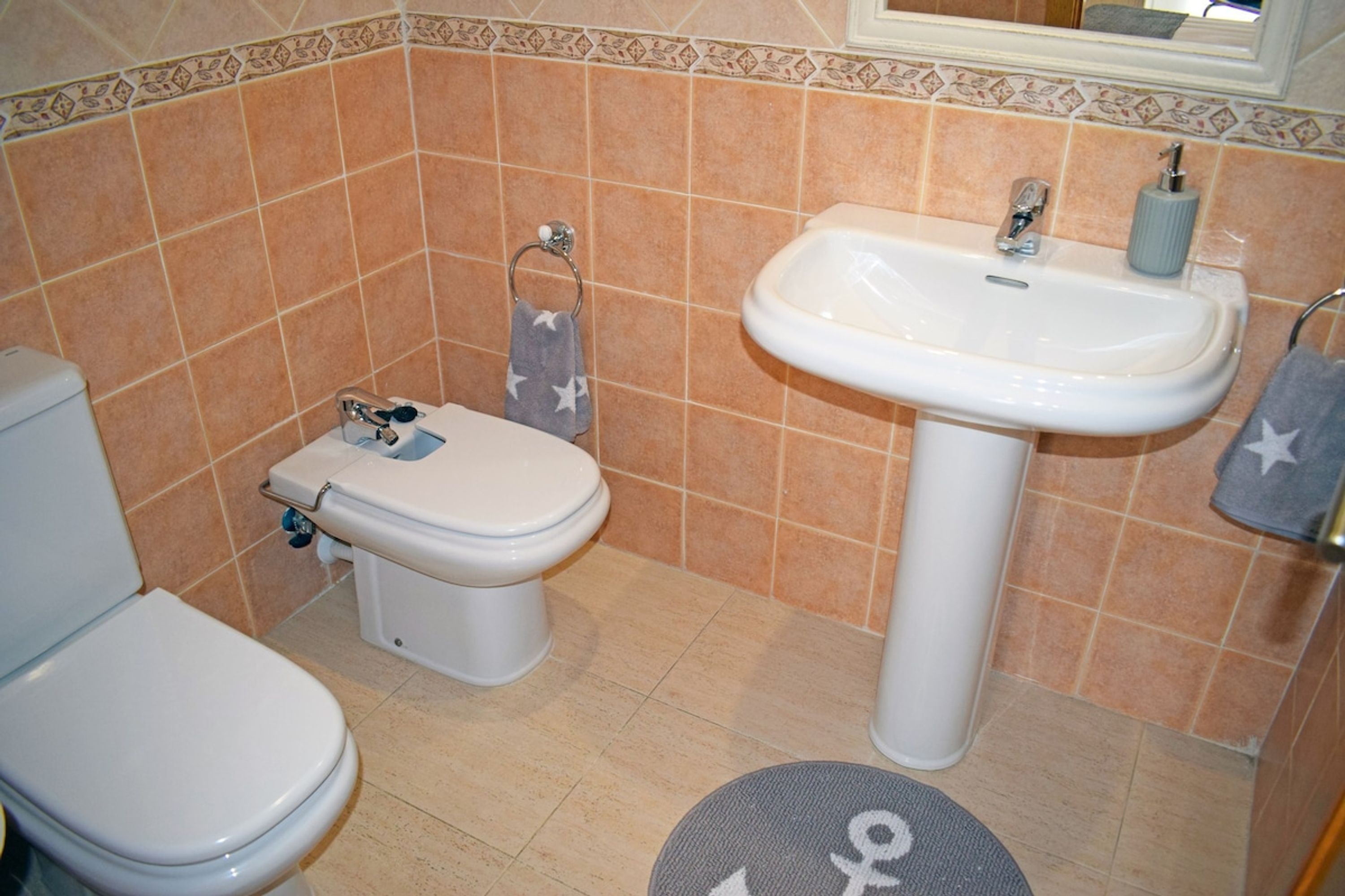 A bathroom with a toilet, sink, and tiled walls.