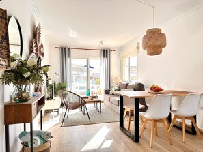 Un soggiorno moderno con zona pranzo, ampie finestre e vista sulla città.
