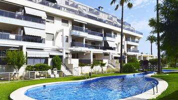 Un hôtel à plusieurs étages doté d’une piscine, de balcons et d’une pelouse bien entretenue.