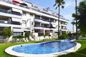 Un hôtel à plusieurs étages doté d’une piscine, de balcons et d’une pelouse bien entretenue.