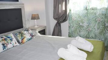 Una cama bien hecha con una colcha verde y dos almohadas con estampado tropical.