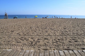 A sandy beach with a wooden walkway, a lifeguard tower, and people walking. - Ap2216 in Denia With 2 Bedrooms and 2 Bathrooms (Denia)